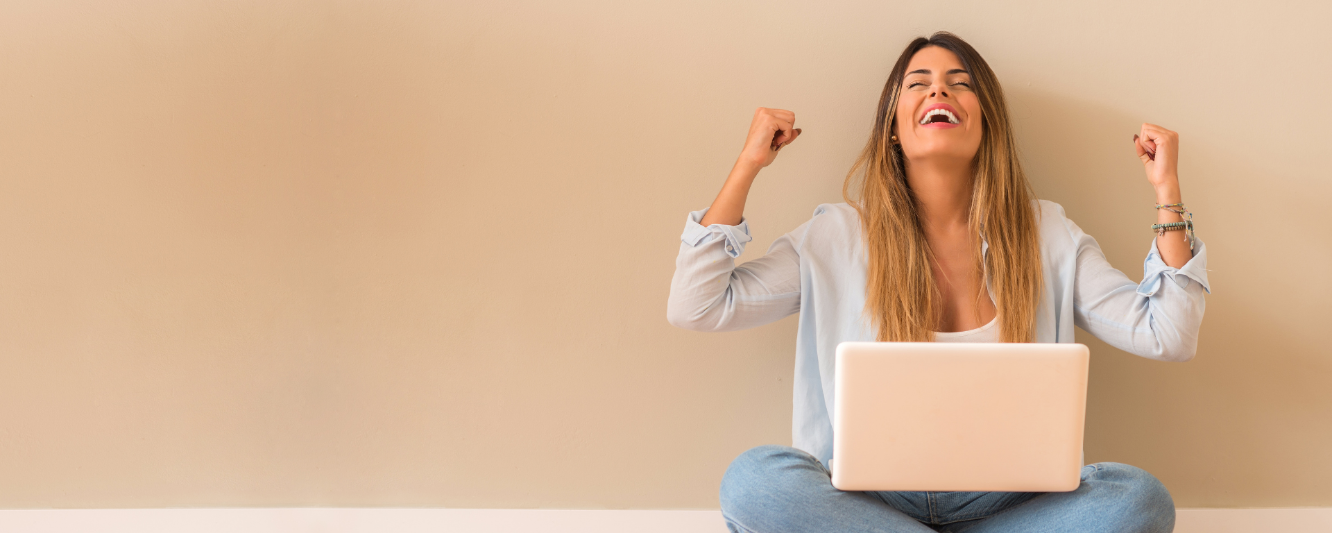 Mujer festeja frente a una computadora. 