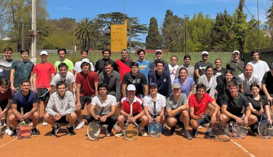Torneo de tenis UM 2022, posan frente a cancha 42 participantes con raquetas al sol