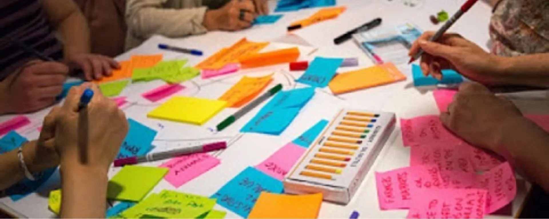 Grupo de personas en una mesa llena de post-its Grupo de personas en una mesa llena de post-its