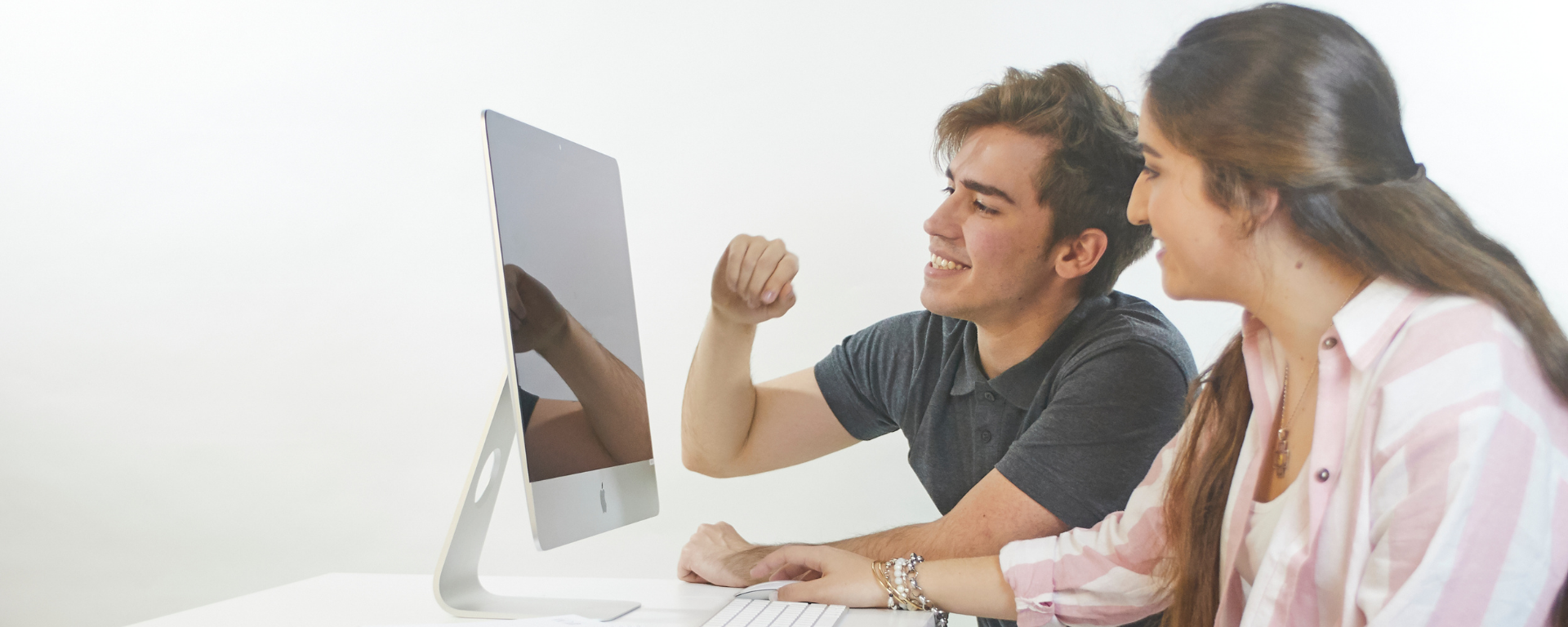 Un chico y una chica miran hacia la pantalla de una computadora.