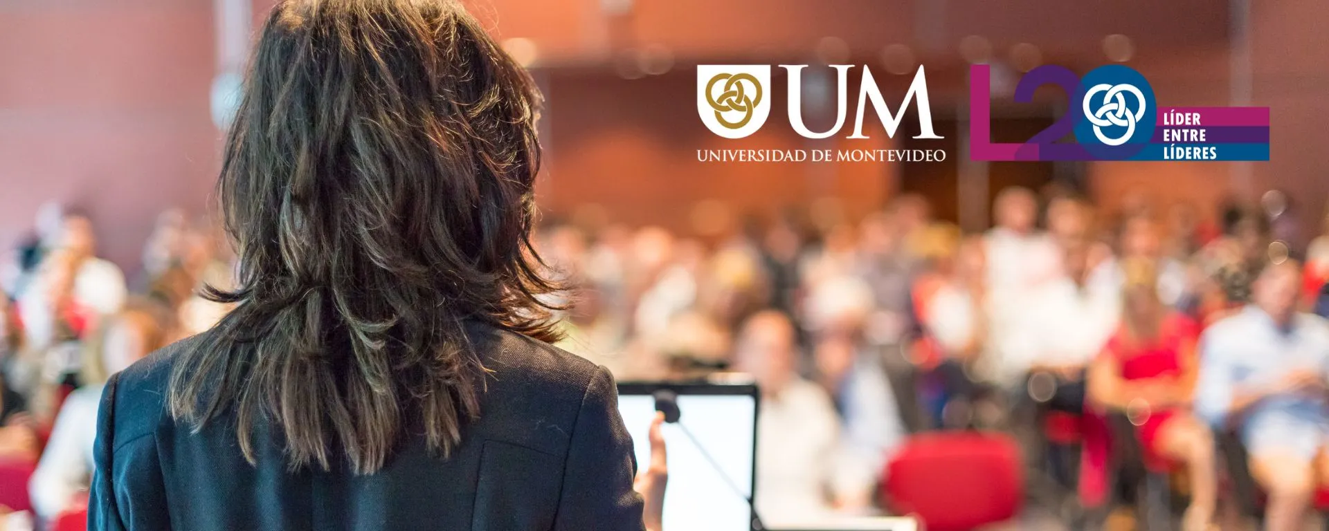 Portada L20, persona de espaldas, enfrenta un grupo de personas desde el podio de oradores Portada L20, persona de espaldas, enfrenta un grupo de personas desde el podio de oradores