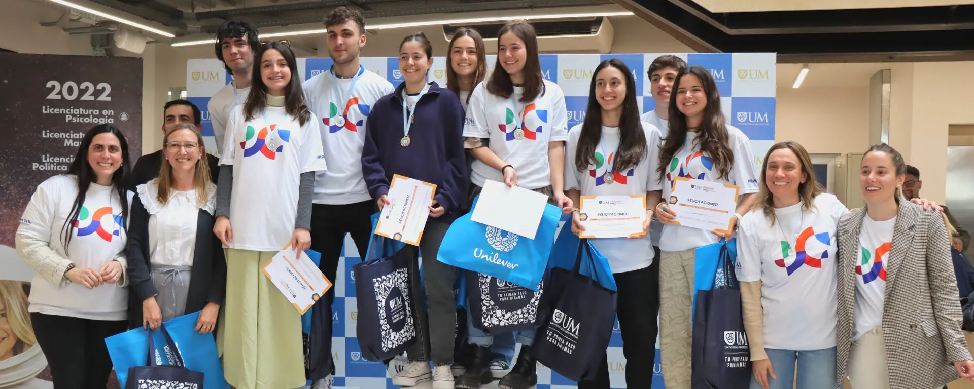 Más de 120 preuniversitarios participaron de la final del Challenge UM 2022 Grupo de preuniversitarios posan con premios, junto a organizadores del Challenge UM. Visten camisetas con formas de colores que identifican a la campaña 2022 de la UM.