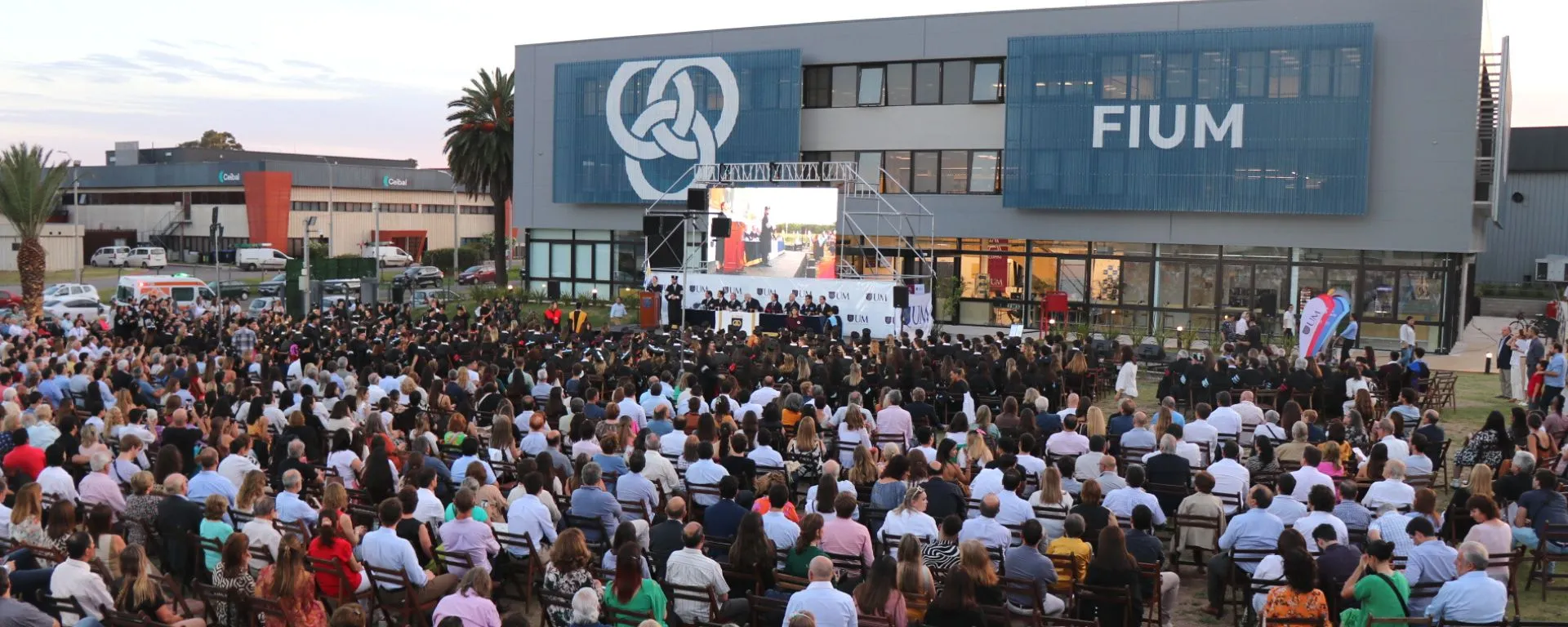 Portada noticia: Se celebró la Graduación UM 2022 Graduación UM 7 de diciembre: público y graduados frente a escenario con autoridades tras la mesa